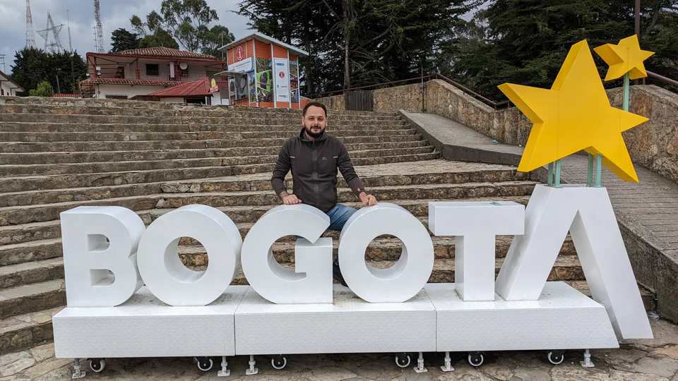 Peter Zošiak pózuje u velkého nápisu „BOGOTÁ“ v hlavním městě Kolumbie Bogota. Kolem jsou kamenné schody a městská vyhlídka.